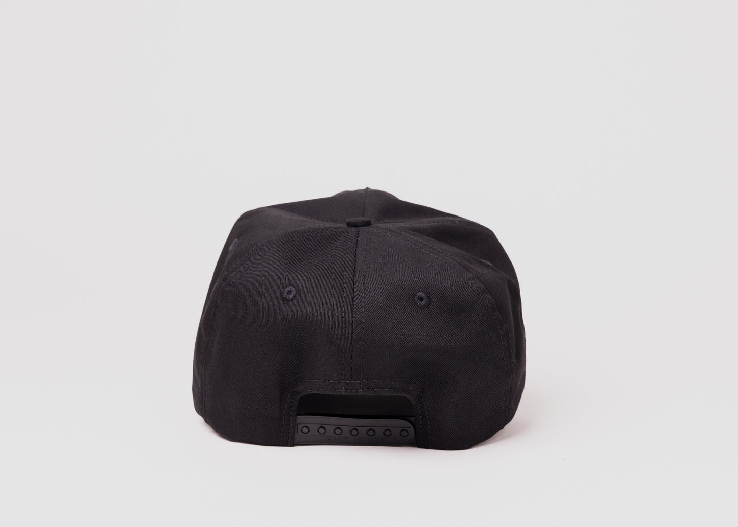 Back view of black Besco hat showing adjustable snapback closure on white background.