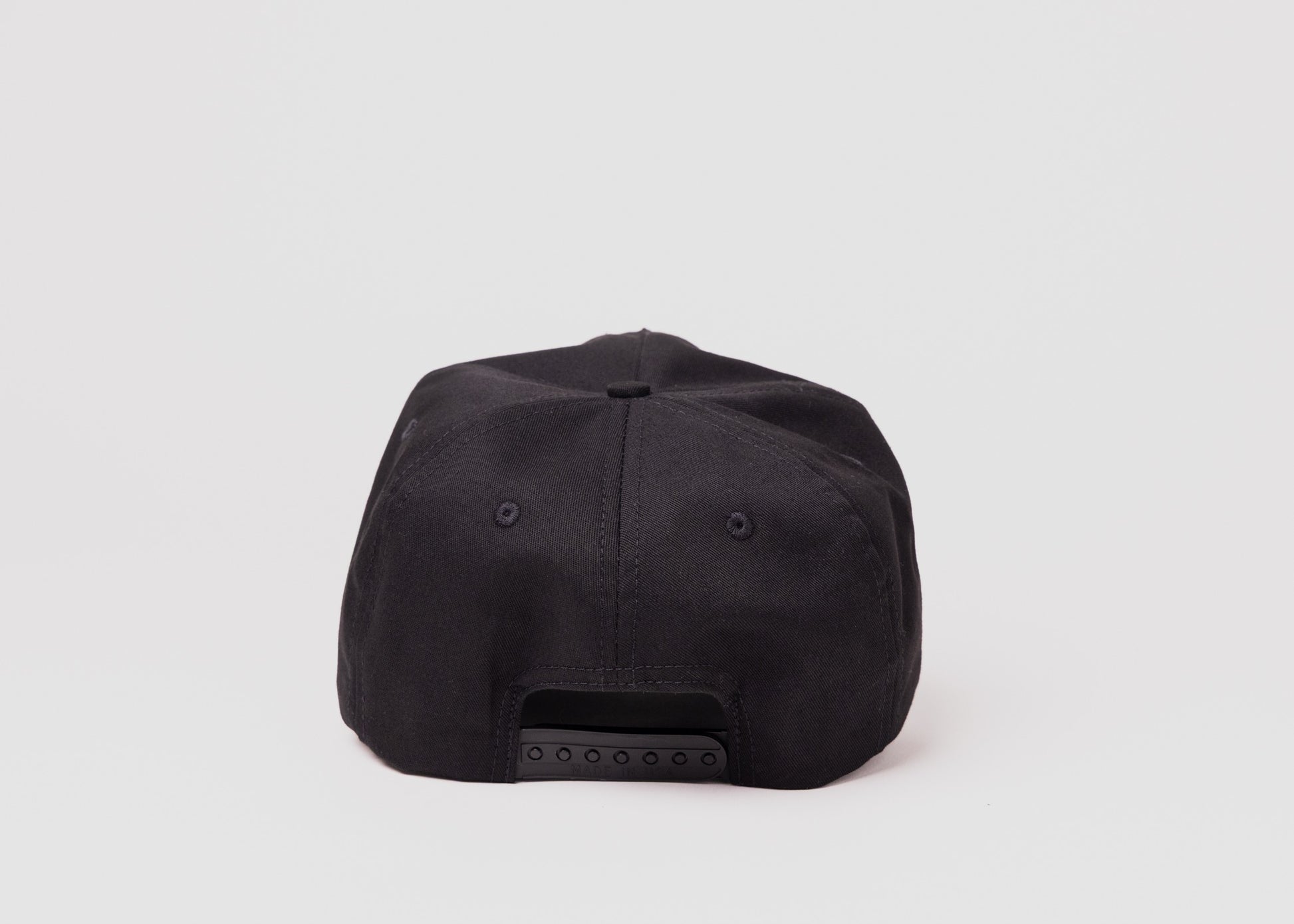 Back view of black Besco hat showing adjustable snapback closure on white background.