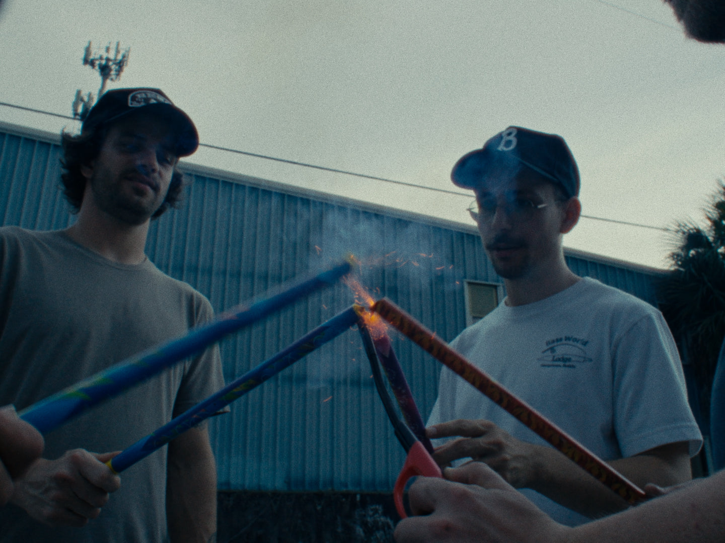 Group of friends lighting fireworks outdoors, one wearing a black Besco hat with a brown and white fox patch.