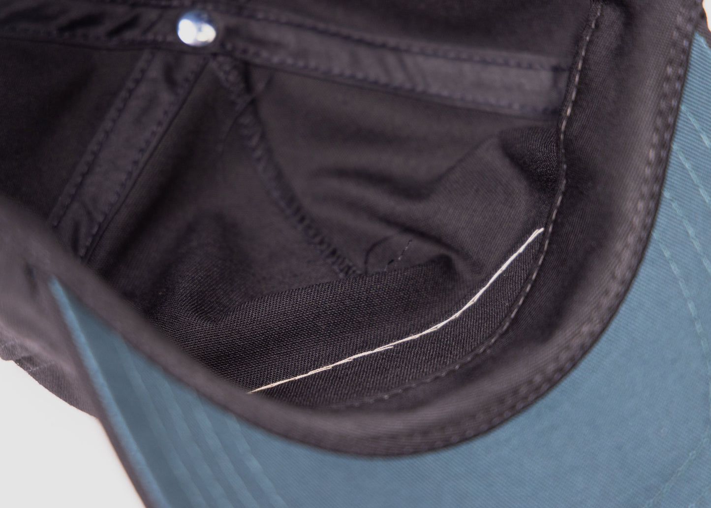 Interior close-up of Besco hat showing green underbill and white hand-stitching used for patch application.