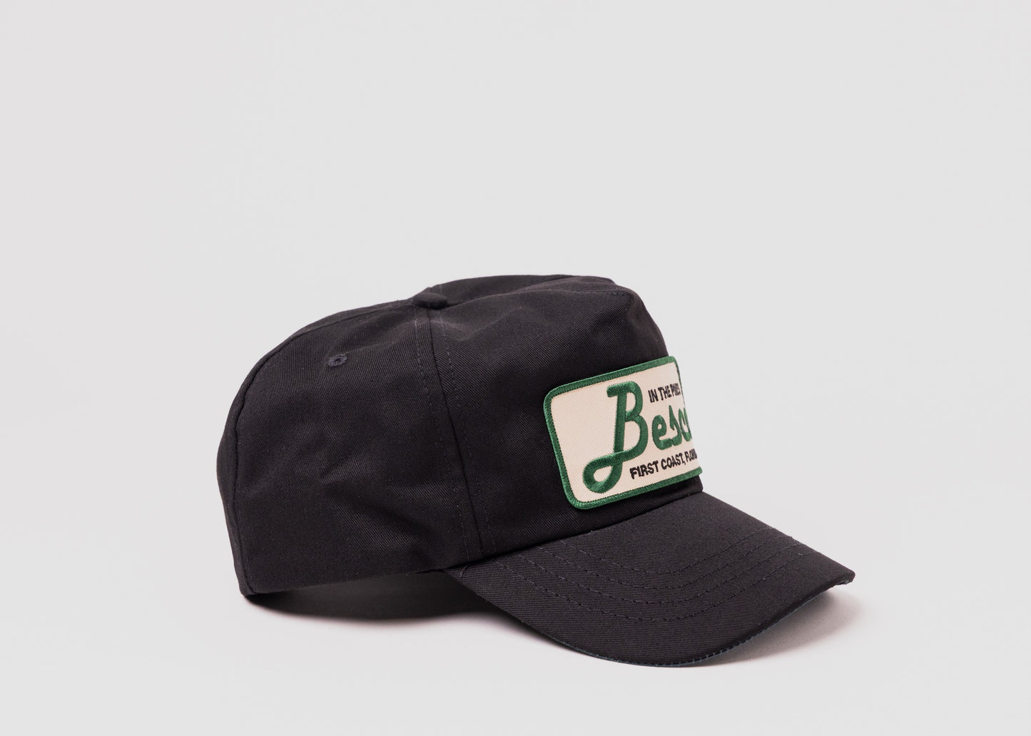 Black Besco hat with "In The Pines" green and tan patch, angled front view on white background.