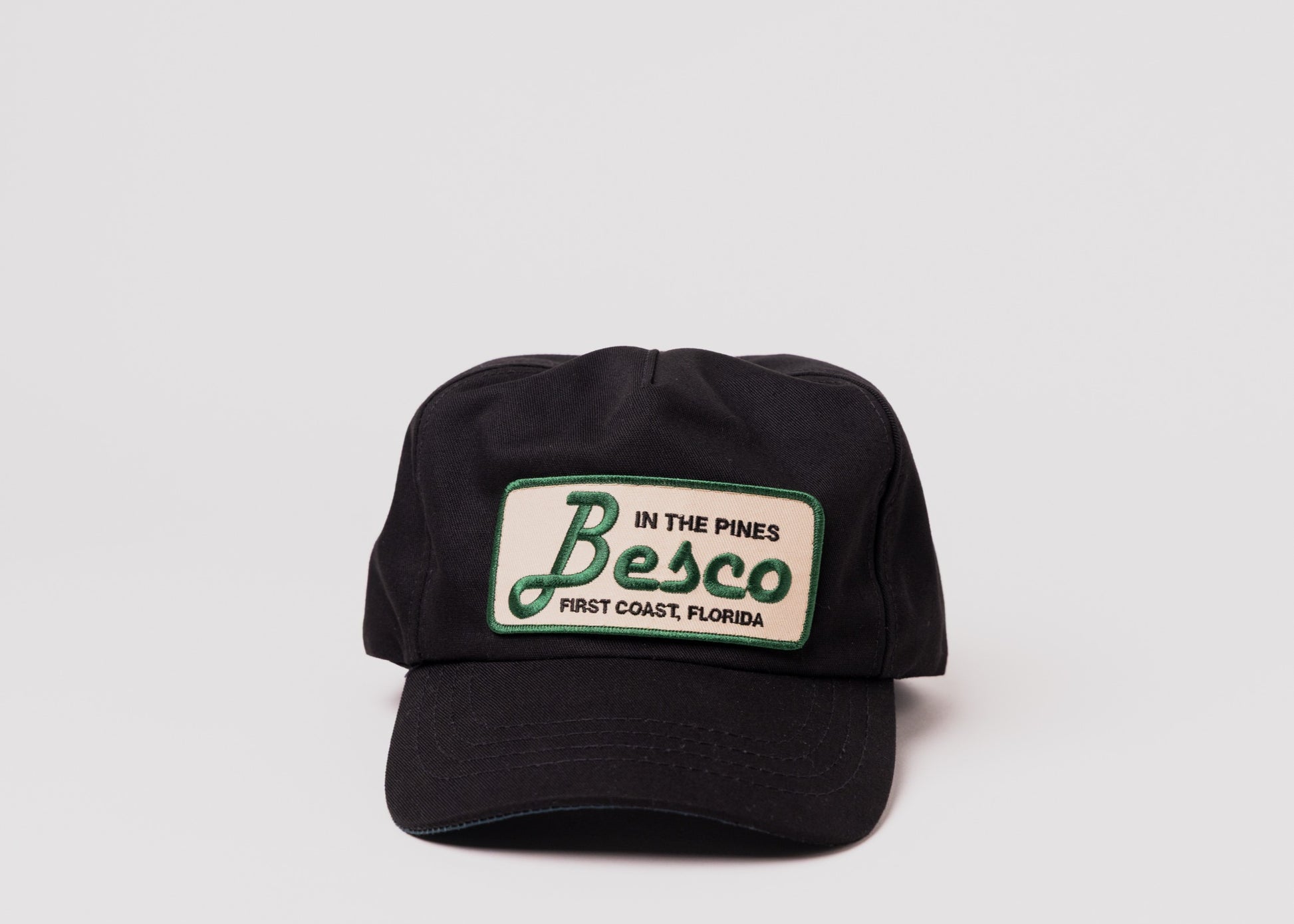 Black Besco hat with "In The Pines" green and tan patch, front view on white background.