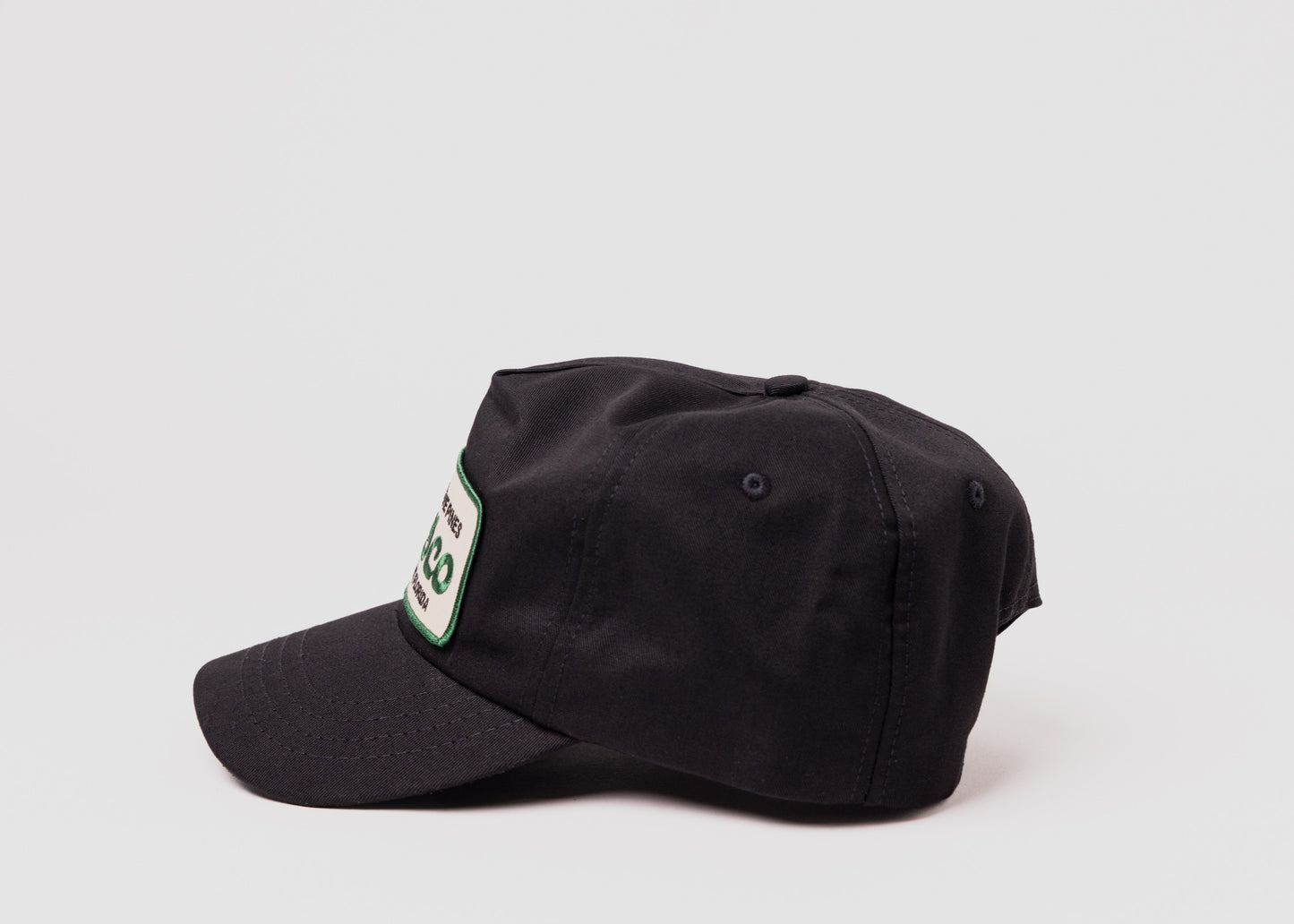 Black Besco hat with "In The Pines" green and tan patch, side profile on white background.