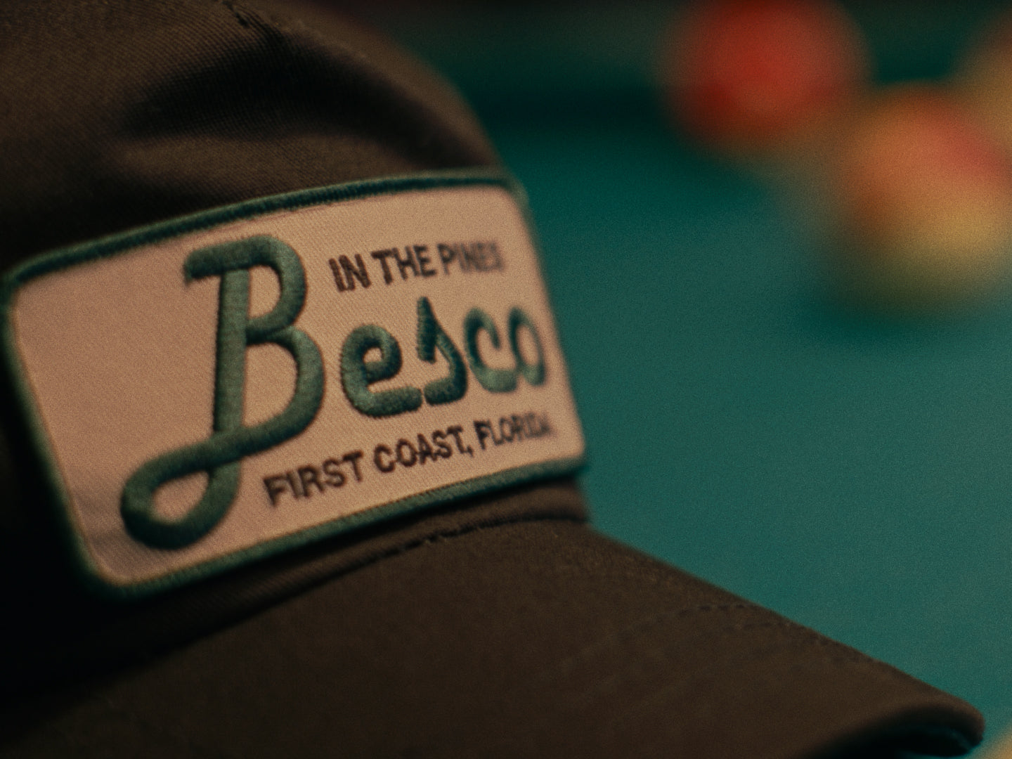 Close-up of the "In the Pines" Besco hat resting on a pool table under bar lighting at Perfect Rack.